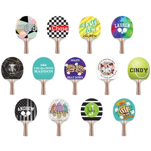 May include: Twelve different designs for table tennis paddles. The designs include names, phrases, and images. Some of the designs include: "Chloe", "Chase", "Game On", "Lauren", "The Real Boss Madison", "Noah's Beat Down", "Cindy", "Andrew", "Kaelyn", "Jake", and "Boom".