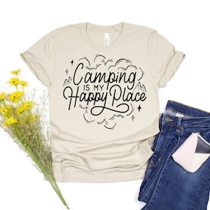 Może przedstawiać: Beżowa koszulka z czarnym nadrukiem, na kt&oacute;rym widnieje napis "Camping is my Happy Place" z wzorem g&oacute;r i chmur.