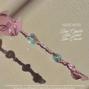 May include: A pink opalite, blue jade, and lilac quartz crystal wand wrapped in copper wire. The wand is made with a pink opalite heart, a blue jade heart, and a lilac quartz point. The wand is approximately 10 inches long. MADE WITH Pink Opalite Blue Jade Lilac Quartz