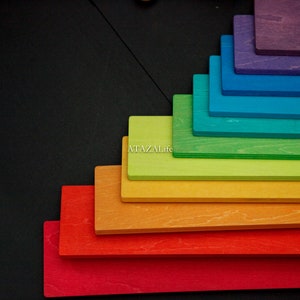 Könnte beinhalten: Ein Set aus rechteckigen Holzbrettern, die in einem kaskadierenden Regenbogenverlauf von Rot bis Violett angeordnet sind. Jedes Brett hat eine sichtbare Holzmaserung und der Text ATAZALife ist in Weiß auf dem gelben Brett aufgedruckt.