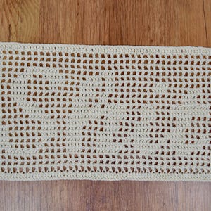 Puede incluir: Tejido de ganchillo crema de tejido abierto. La pieza rectangular presenta un patr&oacute;n repetitivo de peque&ntilde;os agujeros espaciados uniformemente, creando una textura delicada y aireada. El trabajo de ganchillo est&aacute; bien hecho, con una puntada consistente.