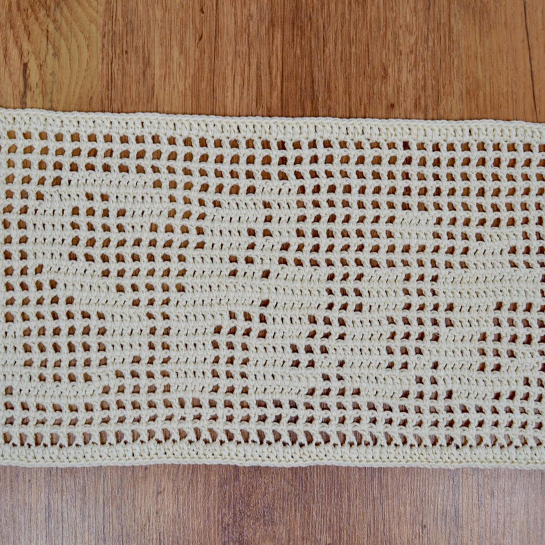 Puede incluir: Tejido de ganchillo crema de tejido abierto. La pieza rectangular presenta un patr&oacute;n repetitivo de peque&ntilde;os agujeros espaciados uniformemente, creando una textura delicada y aireada. El trabajo de ganchillo est&aacute; bien hecho, con una puntada consistente.