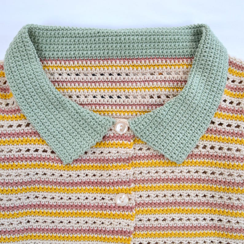 Puede incluir: Un su&eacute;ter de crochet a rayas con un cuello verde y botones blancos. El su&eacute;ter tiene un patr&oacute;n de rayas rosa claro, crema y amarillo.