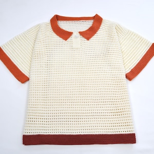 Pode incluir: Camisa polo de croch&ecirc; creme com mangas curtas. A camisa apresenta gola, acabamento das mangas e bainha em cor ferrugem. Um &uacute;nico bot&atilde;o &eacute; vis&iacute;vel na gola. O design de tecido aberto adiciona uma textura &uacute;nica a esta blusa casual.