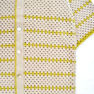 Puede incluir: Camisa de crochet color crema con botones y mangas cortas. La camisa presenta un patr&oacute;n repetitivo de formas de diamante amarillas. Los bordes y la tapeta de botones son de color crema a juego.