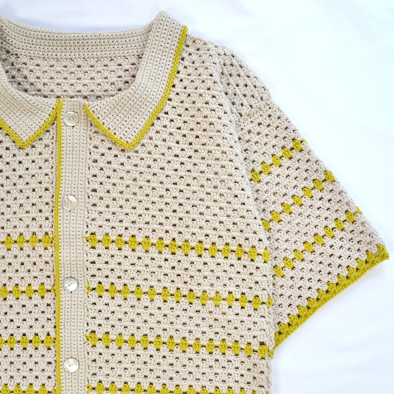 Puede incluir: Camisa de crochet beige con botones y mangas cortas. La camisa presenta un ribete chartreuse en contraste a lo largo del cuello, las mangas y la tapeta de los botones. El patr&oacute;n de crochet incluye formas de diamante chartreuse.