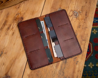 May include: A brown leather wallet with multiple card slots and a money clip. The wallet is open and shows several cards and cash inside.