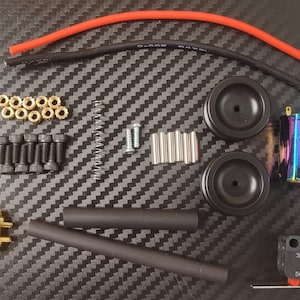 May include: A set of hobby motor parts including two rainbow colored motors, two black wheels, a spring, a switch labeled "V-212-10C 3-12 V", a yellow connector, black heat shrink tubing, black and red wire, and various screws and nuts.