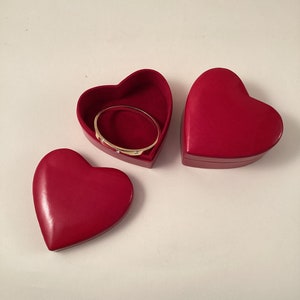 May include: Three red heart-shaped boxes, one open with a gold bangle inside.