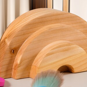 May include: Three wooden half-circle shapes stacked on top of each other, forming a rounded arch. The wood is a light natural color.