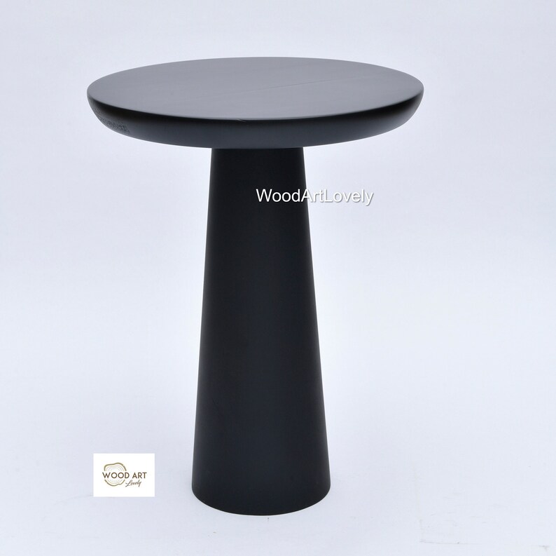 Op de afbeelding: Een zwarte houten bijzettafel met een rond blad en een conische basis. De tafel is gemaakt van massief hout en heeft een gladde afwerking. De tafel is ongeveer 50 cm hoog en 40 cm in diameter.