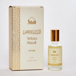 May include: A bottle of White Musk Attar perfume with a gold cap and a matching box. The box is beige with gold filigree and text. The perfume bottle is 30ml and alcohol-free.