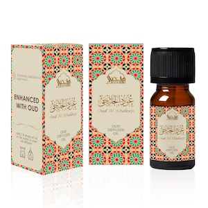 May include: A brown glass bottle with a gold label that says "Oud Al Khaleeji" and "OUD DIFFUSER OIL". The bottle is sitting on a white surface with a larger box behind it. The box has a similar design to the bottle and says "ENHANCED WITH OUD" and "OUD DIFFUSER OIL".