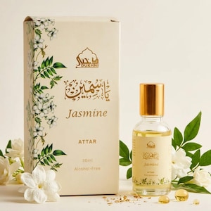 May include: A clear glass bottle of Jasmine Attar perfume with a gold cap, next to a matching box. The box and bottle are decorated with floral designs and the words "Jasmine" and "Attar". The bottle contains 30ml of alcohol-free perfume.