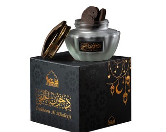 Pode incluir: Uma caixa preta com letras douradas que dizem "Dukhoon Al Khaleej" e um logotipo dourado de uma mesquita. A caixa contém um frasco de vidro com tampa dourada e incenso preto dentro.