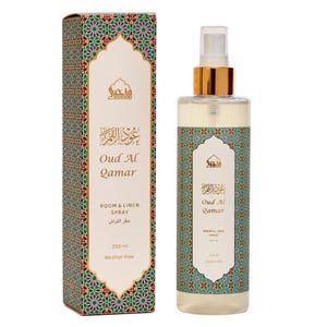 May include: A room and linen spray bottle and box set. The bottle has a gold cap and a clear liquid. The box and bottle are decorated with a geometric pattern in green, red, and gold. The text "Oud Al Qamar" is displayed on both.