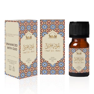 May include: A brown glass bottle with a black cap containing Oud Ya Aini diffuser oil. The bottle is labeled with Arabic script and the words "Oud Ya Aini" and "Oud Diffuser Oil". The bottle is sitting on a white surface.