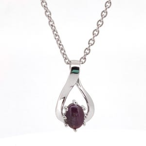 Op de afbeelding: Zilverkleurige ketting met een hanger. De hanger heeft een donkerpaarse, ovale edelsteen. De hanger heeft een druppelvormig ontwerp en de ketting is delicaat. De edelsteen is het middelpunt, in een prong setting.