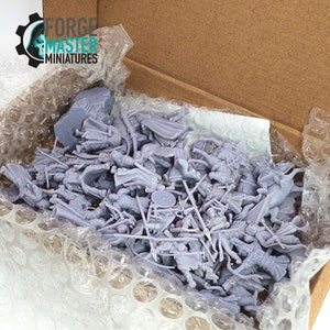 May include: A box filled with unpainted grey plastic miniature figures of warriors and horses. The box is lined with bubble wrap for protection during shipping. The box has a label that says "FORGE MASTER MINIATURES".