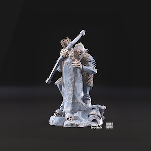 Puede incluir: Una figura en miniatura detallada de un guerrero Orc gruñendo, pintado en tonos de azul y blanco, sosteniendo un arco y una flecha. El Orc está encaramado en una base rocosa con cráneos y el texto "Ring of Legends" y "Cavale Games".