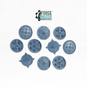 May include: Ten different styles of miniature shields, all painted in a light blue colour. The shields have various designs, including spikes, crosses, and circles.