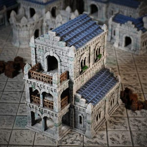 Peut inclure: Un bâtiment miniature en pierre détaillé avec un toit en tuiles bleues, plusieurs balcons et des fenêtres cintrées. Le bâtiment est peint dans un style réaliste et a un aspect vieilli.