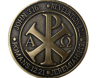May include: A gold-colored metal coin with a Christian symbol in the center. The coin has the text "JOHN 3:16", "ROMANS 12:21", "JEREMIAH 1:19", and "REVELATION 12:11" around the edge.