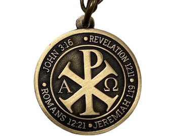 May include: A gold-toned pendant necklace with a round charm featuring a Christian symbol, the Chi Rho, with the Greek letters Alpha and Omega. The charm is surrounded by a circle with the words "John 3:16", "Romans 12:21", "Jeremiah 1:19", and "Revelation 12:11".