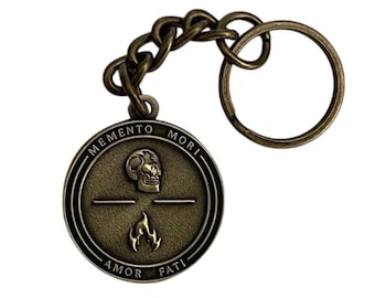 May include: Antique bronze keychain with a round pendant. The pendant features a skull, a flame, and the phrases "MEMENTO MORI" and "AMOR FATI". The keychain includes a chain and a key ring.