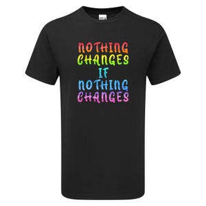 May include: A black short-sleeve t-shirt featuring the text "NOTHING CHANGES IF NOTHING CHANGES" printed in a multi-colored, textured font. The words are stacked in four lines with rainbow-inspired hues including red, yellow, green, blue, and pink.