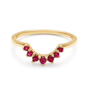May include: A gold band ring with a curved row of red ruby gemstones.