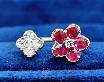 May include: A white gold ring with two flower designs. One flower is made of red rubies and the other is made of white diamonds.
