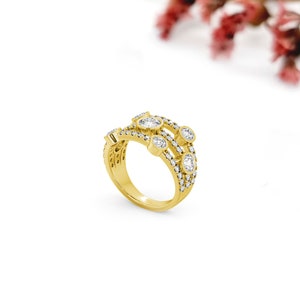 May include: A gold ring with multiple rows of small diamonds and larger oval-shaped diamonds. The ring is set on a white background.