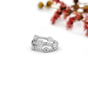 May include: A silver ring with a row of small diamonds and three larger round diamonds set in the band.