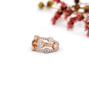 May include: A rose gold ring with a row of small diamonds and five larger bezel-set diamonds.