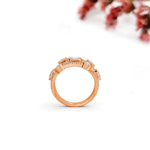 May include: A rose gold band ring with multiple small, clear, square-shaped diamonds set in a pave setting.