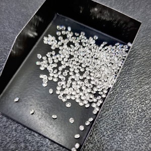 May include: A black tray filled with a large quantity of small, round, clear diamonds.