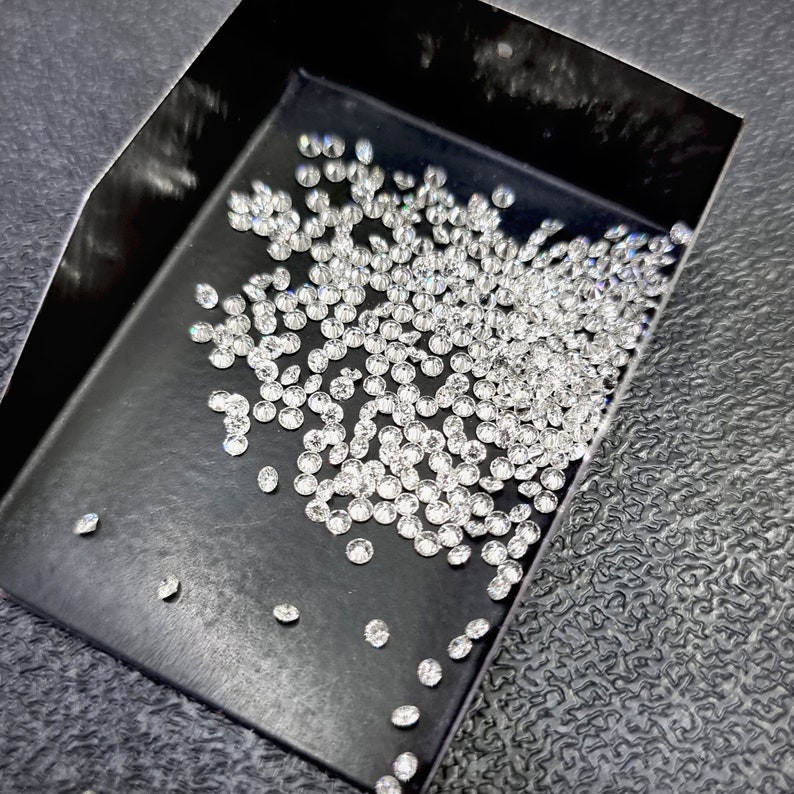 May include: A black tray filled with a large quantity of small, round, clear diamonds.