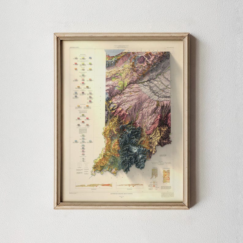May include: Framed 3D topographical map of Indiana, showing a detailed relief of the state's terrain. The map is in a light-coloured wooden frame. The map uses various colours to represent different elevations and geographical features.