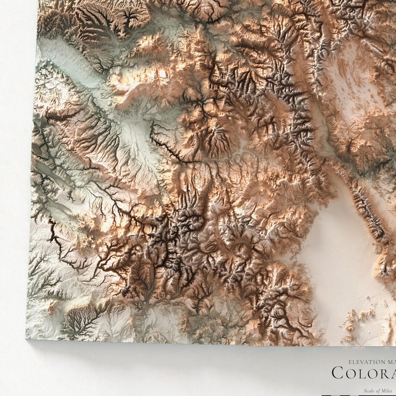 K&ouml;nnte beinhalten: Eine detaillierte, dreidimensionale H&ouml;henkarte von Colorado mit einem Reliefdesign in Braun-, Beige- und Wei&szlig;t&ouml;nen. Die Karte hebt das bergige Gel&auml;nde und die geografischen Merkmale des Staates hervor. Der Text "COLORADO" ist sichtbar.