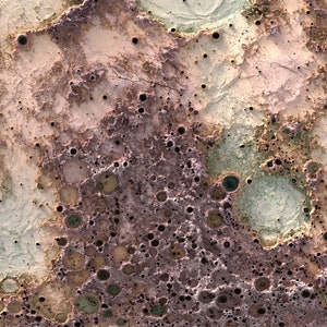 May include: A close-up of a textured surface with a variety of colors, including brown, pink, green, and white. The surface is covered in small holes and craters, giving it a rough and uneven appearance.