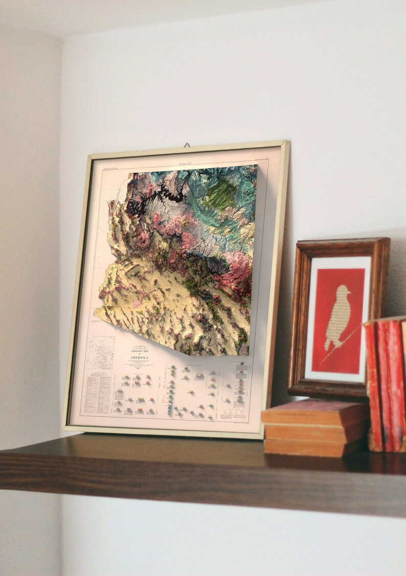 May include: A framed vintage map of Arizona with a 3D relief effect. The map is in shades of brown, green, and pink, and shows the state's topography. The map is titled "Geological Map of Arizona".