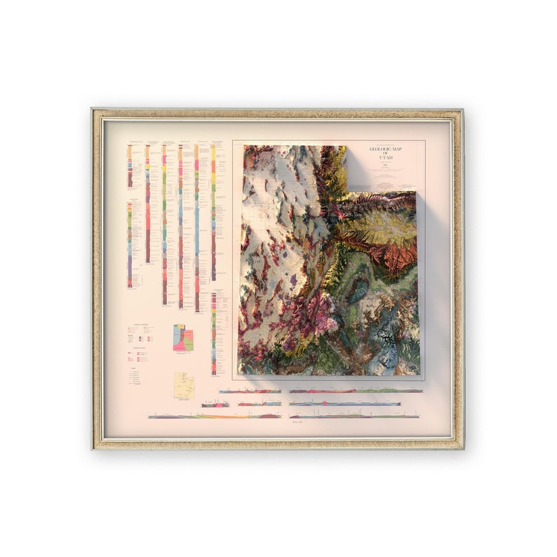 May include: A framed geological map of Utah with a 3D relief map of the state. The map is in a beige frame with a white mat. The map is colorful and shows the different geological formations in the state.