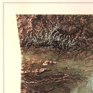 K&ouml;nnte beinhalten: Eine Luftaufnahme einer Bergregion mit braunem, gr&uuml;nem und wei&szlig;em Gel&auml;nde. Das Bild zeigt eine Vielzahl von Landformen, darunter H&uuml;gel, T&auml;ler und Fl&uuml;sse.