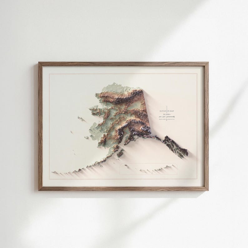 May include: A framed 3D elevation map of Alaska, showcasing the state's topography with detailed relief. The map features a blend of brown, green, and white hues, set against a neutral background. The wooden frame adds a classic touch.