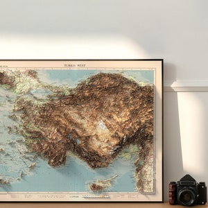 May include: A vintage-style map of Turkey West, showing the topography of the region in brown and green hues. The map is framed in a black frame and has a scale of 1:1,000,000.