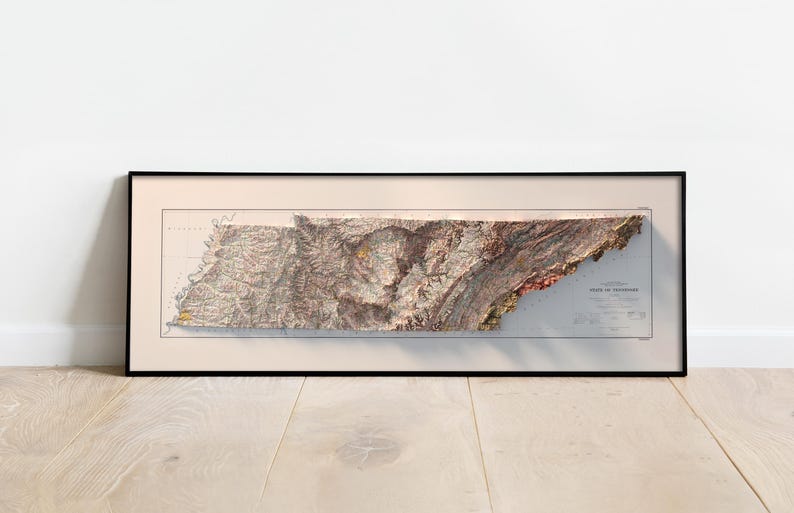 May include: A framed vintage map of the state of Tennessee, showing the topography of the state in a 3D relief style. The map is printed in shades of brown, green, and red, and is surrounded by a black frame.