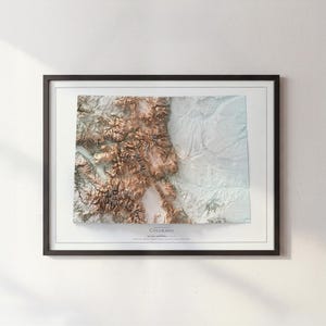 K&ouml;nnte beinhalten: Eine gerahmte topografische Karte von Colorado mit kontrastreichem Reliefdesign. Der westliche Teil zeigt detaillierte braune Gebirgsz&uuml;ge, w&auml;hrend der &ouml;stliche Bereich flache, helle Ebenen darstellt. Der Text lautet Topographic Map of Colorado.