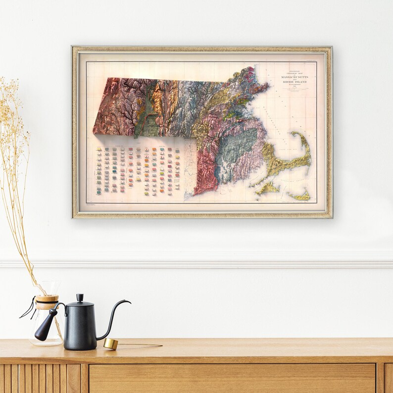 May include: A vintage map of Massachusetts and Rhode Island, showing the state's topography in a 3D relief style. The map is printed in a variety of colors, including green, brown, blue, and yellow. The map is framed in a simple, gold-colored frame.