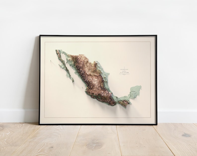 May include: Framed topographical map of Mexico, featuring a 3D relief in shades of brown and green. The map is set against a cream-colored background, enclosed in a black frame. The map includes text indicating elevation and location.